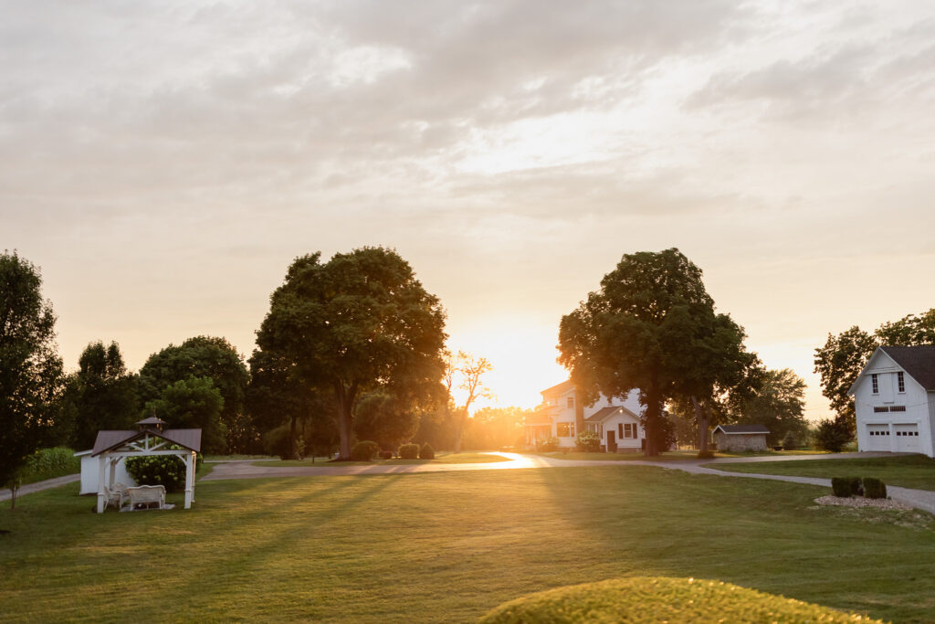 Golden hour sunset over The Wells Estate featuring expansive lawns, historic buildings, and tree-lined countryside views in Upstate New York, ideal for outdoor weddings and events.