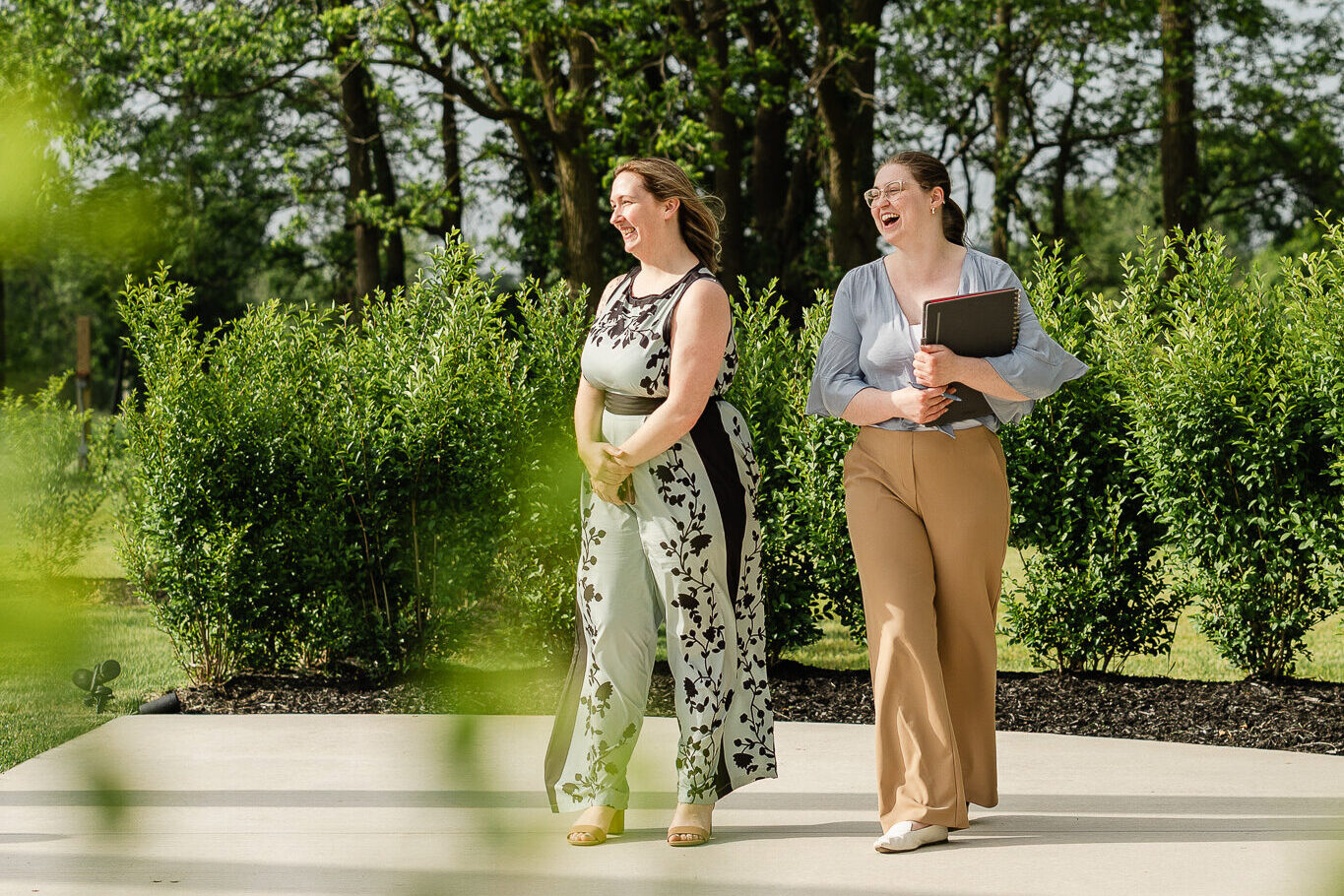 A venue director and venue coordinator walk together during a rehearsal at The Wells Estate, preparing for the ceremony and finalizing wedding day details on the outdoor patio.