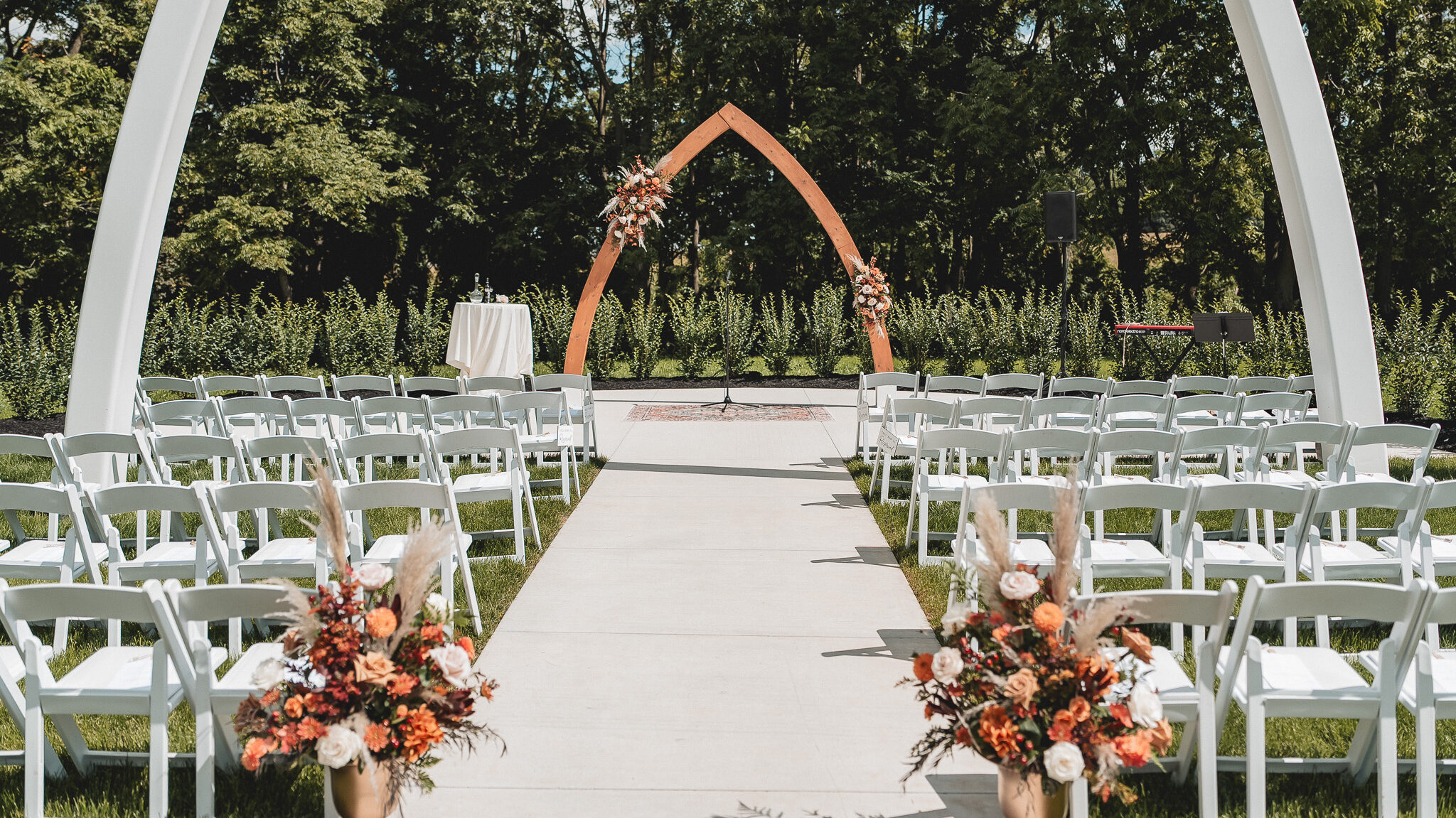 Outdoor wedding ceremony space with white arches and aisle at The Wells Estate.