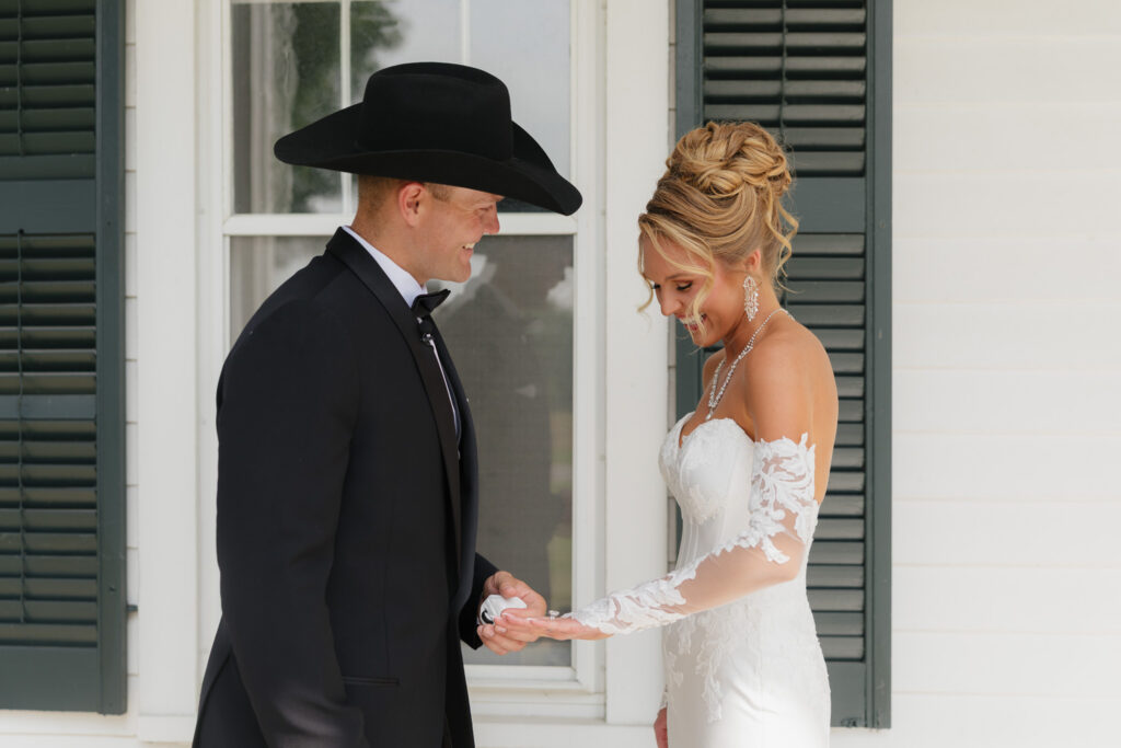 Bride shows her wedding ring to the groom during their first look outside the Estate House at The Wells Estate.