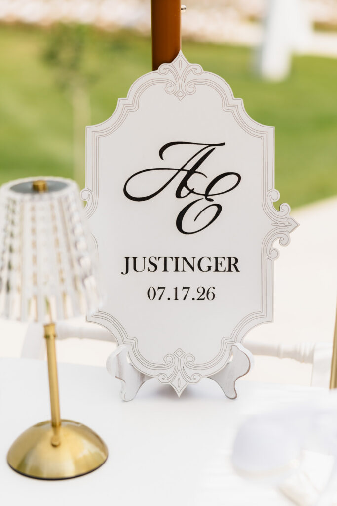 Personalized white wedding sign featuring an A and E monogram, Justinger surname, and July 17, 2026 wedding date at The Wells Estate.
